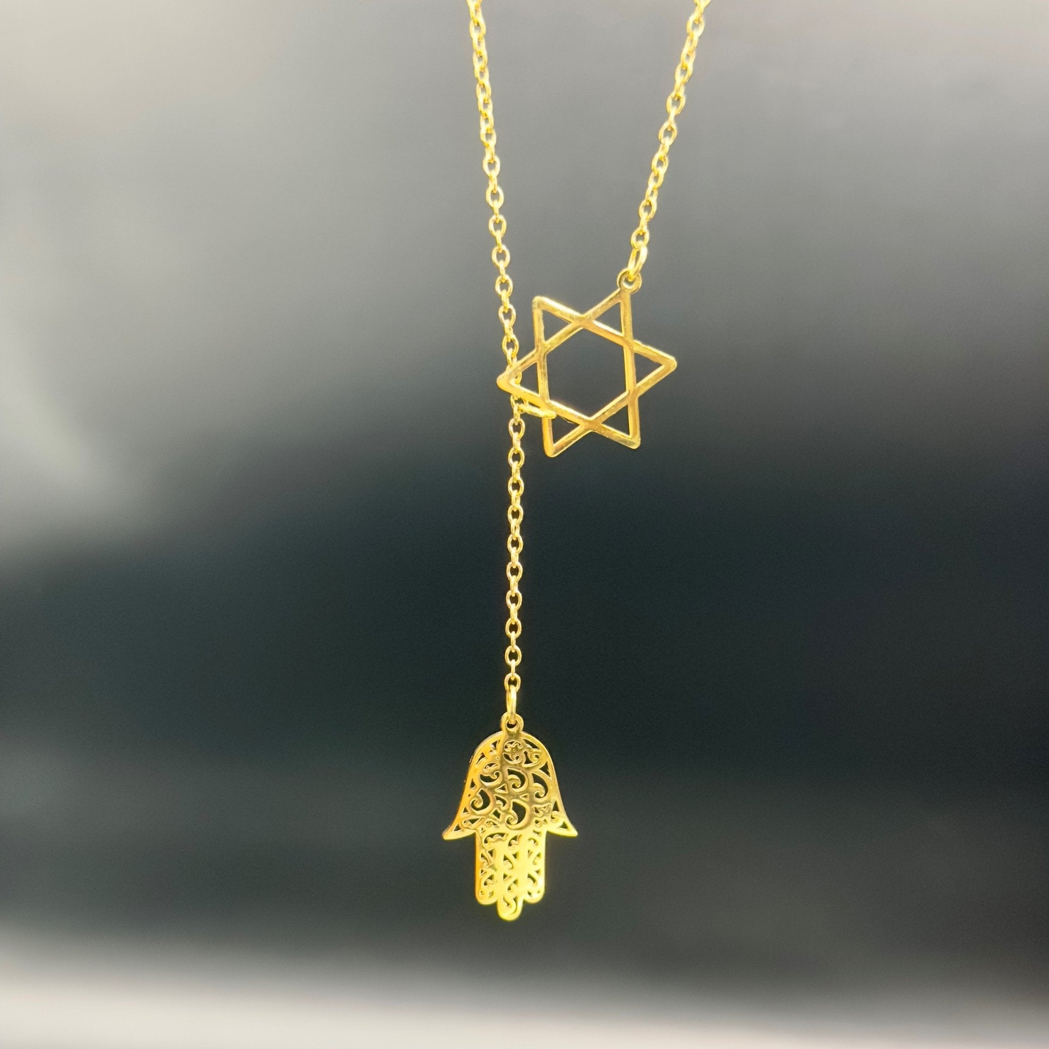 Star of David and Hamsa Drop Necklace - Simply Just Deals LLCStar of David and Hamsa Drop NecklaceJewelry Pendant Necklace42560115703831GoldThe Star of David and Hamsa Drop Necklace features a gold - plated Star of David pendant with a filigree Hamsa hand charm below, displayed against a dark, blurred background.